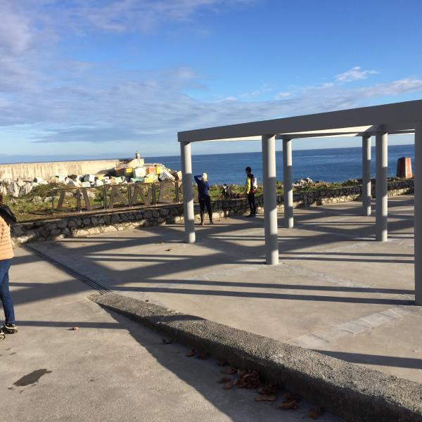 Tendedero de redes y rótulo de Llanes con los Cubos de la Memoria al fondo.